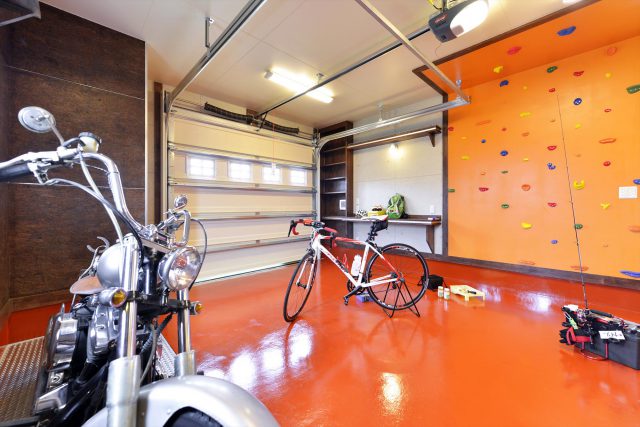 ガレージにあるボルタリング壁は、床の色に合わせたオレンジ色でポップなイメージに